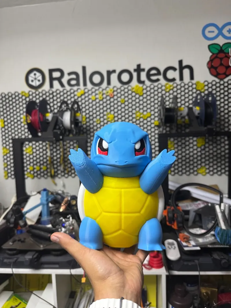 Figura de Squirtle en taller impresas en 3D en el taller Ralorotech; fondo con logo y material de impresión