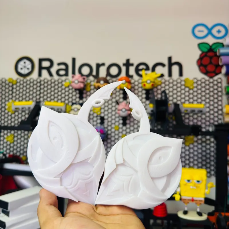 Par de piezas blancas para cosplay impresas en 3D con patrón geométrico, sostenidas en el taller